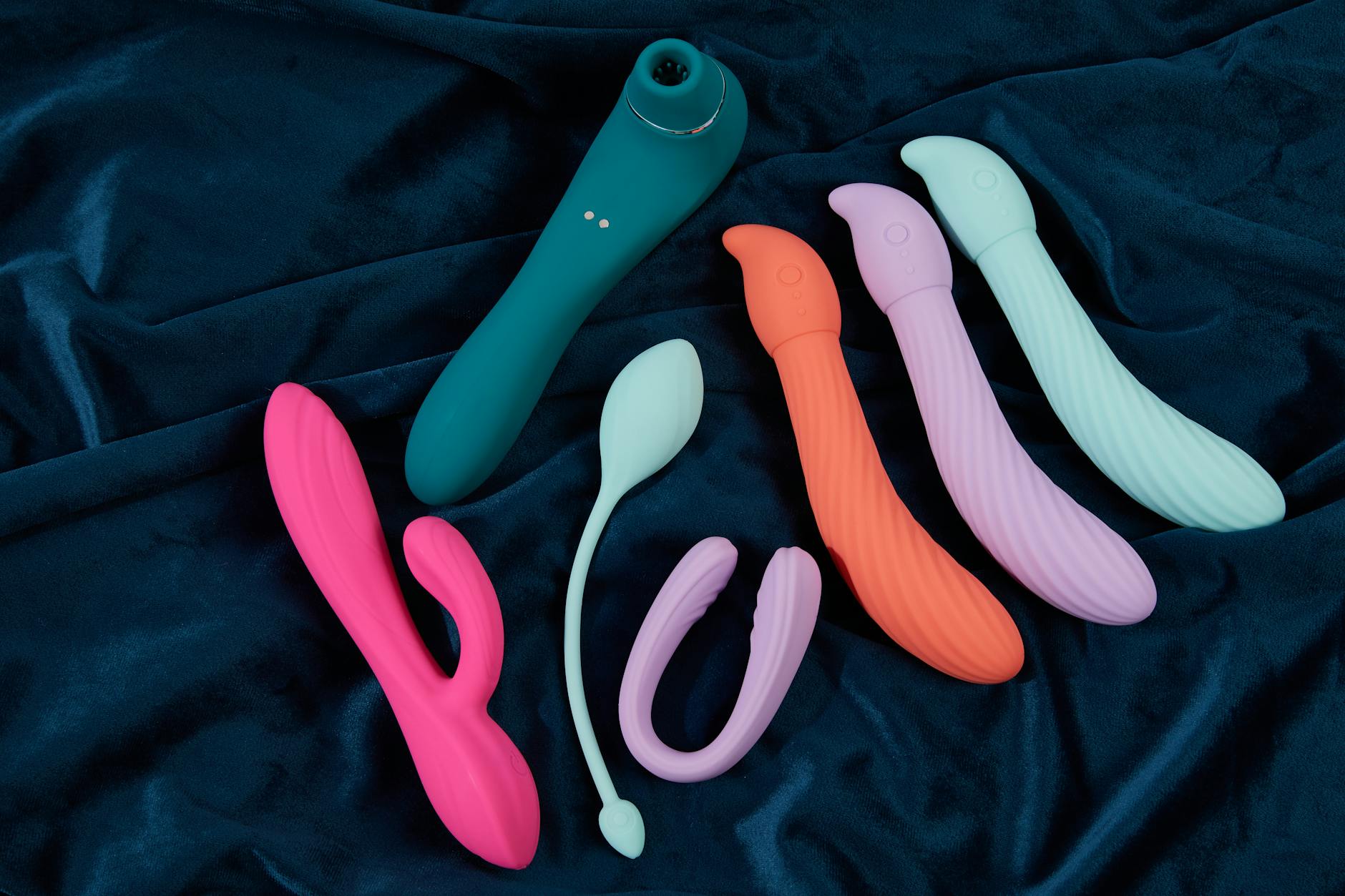 Blue silicone vibrator held gently in hand against purple background