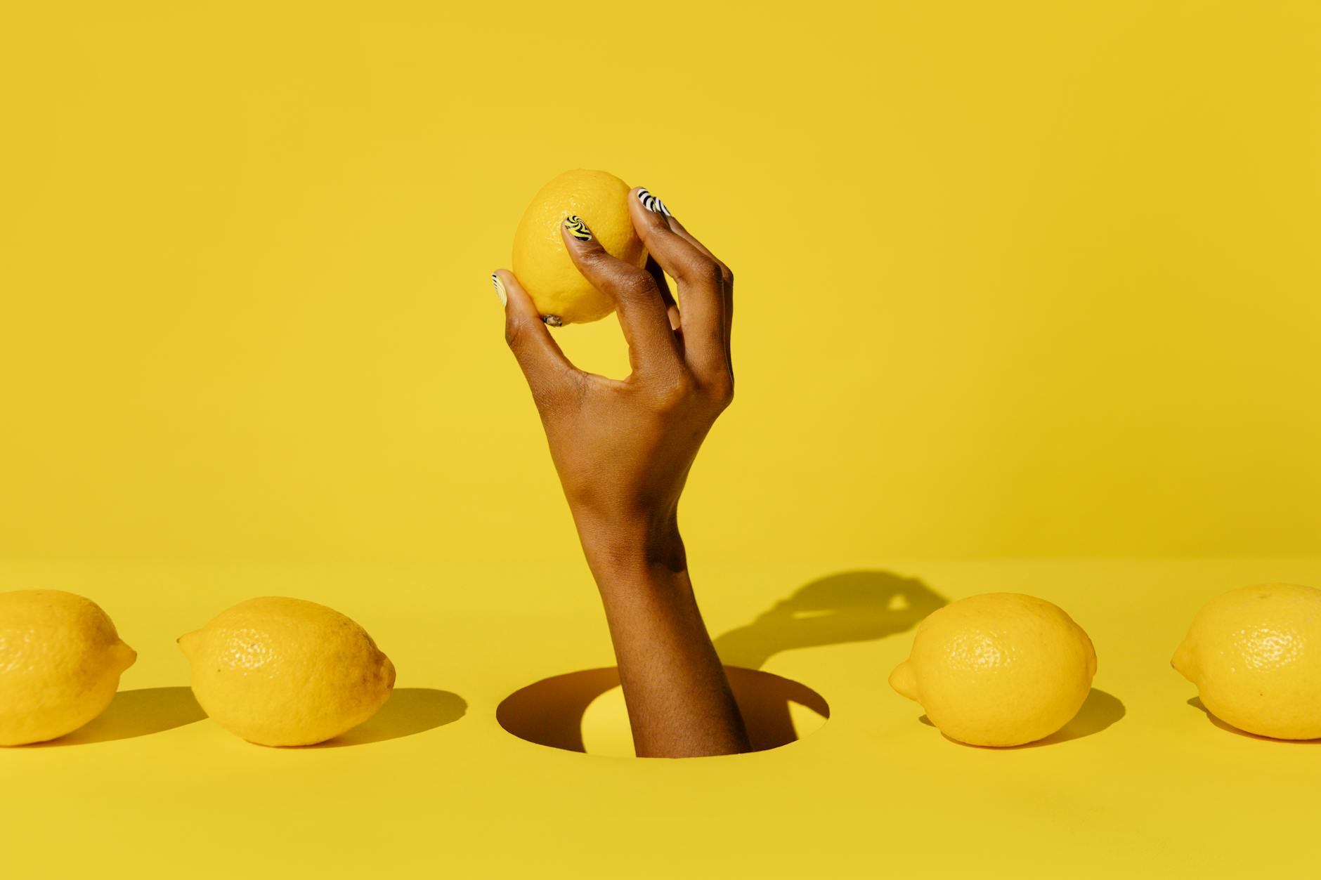 A hand holding a lemon against a vivid yellow background, symbolizing renewal and reconnection