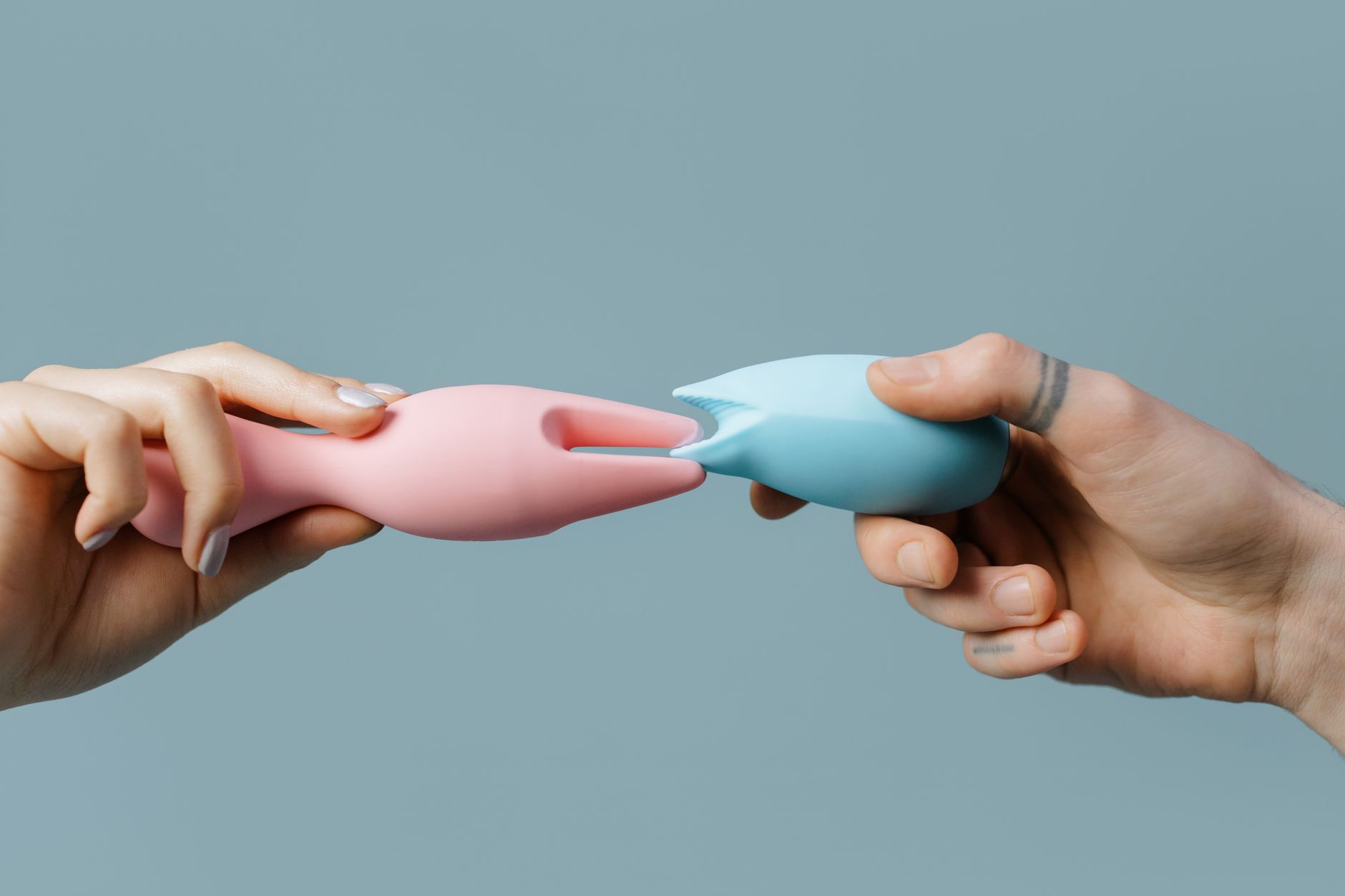 Hands holding colorful lemon-shaped silicone toys on a neutral background
