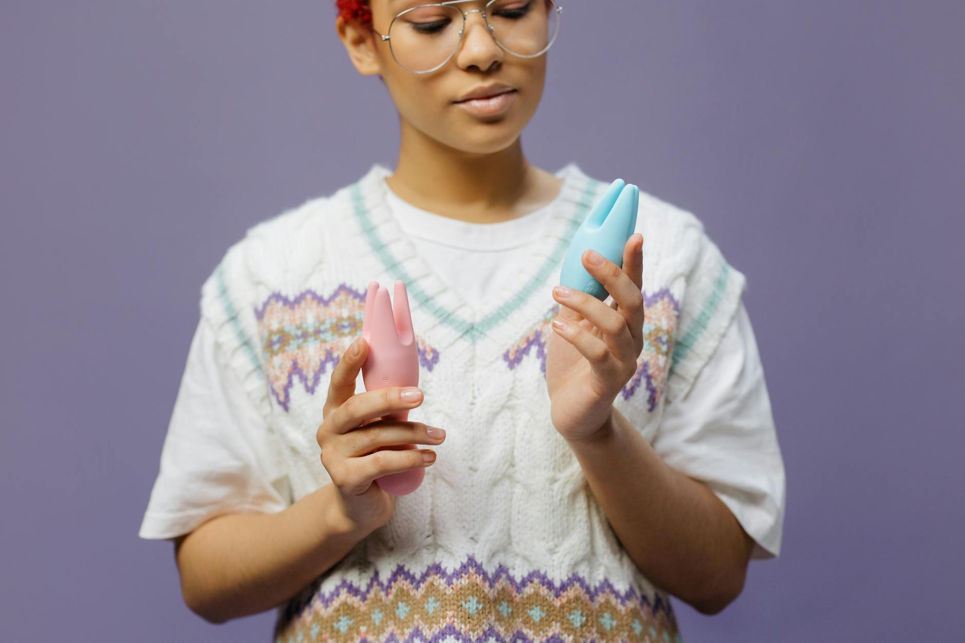 Woman holding colorful clitoral vibrators in contemplative manner during recovery journey