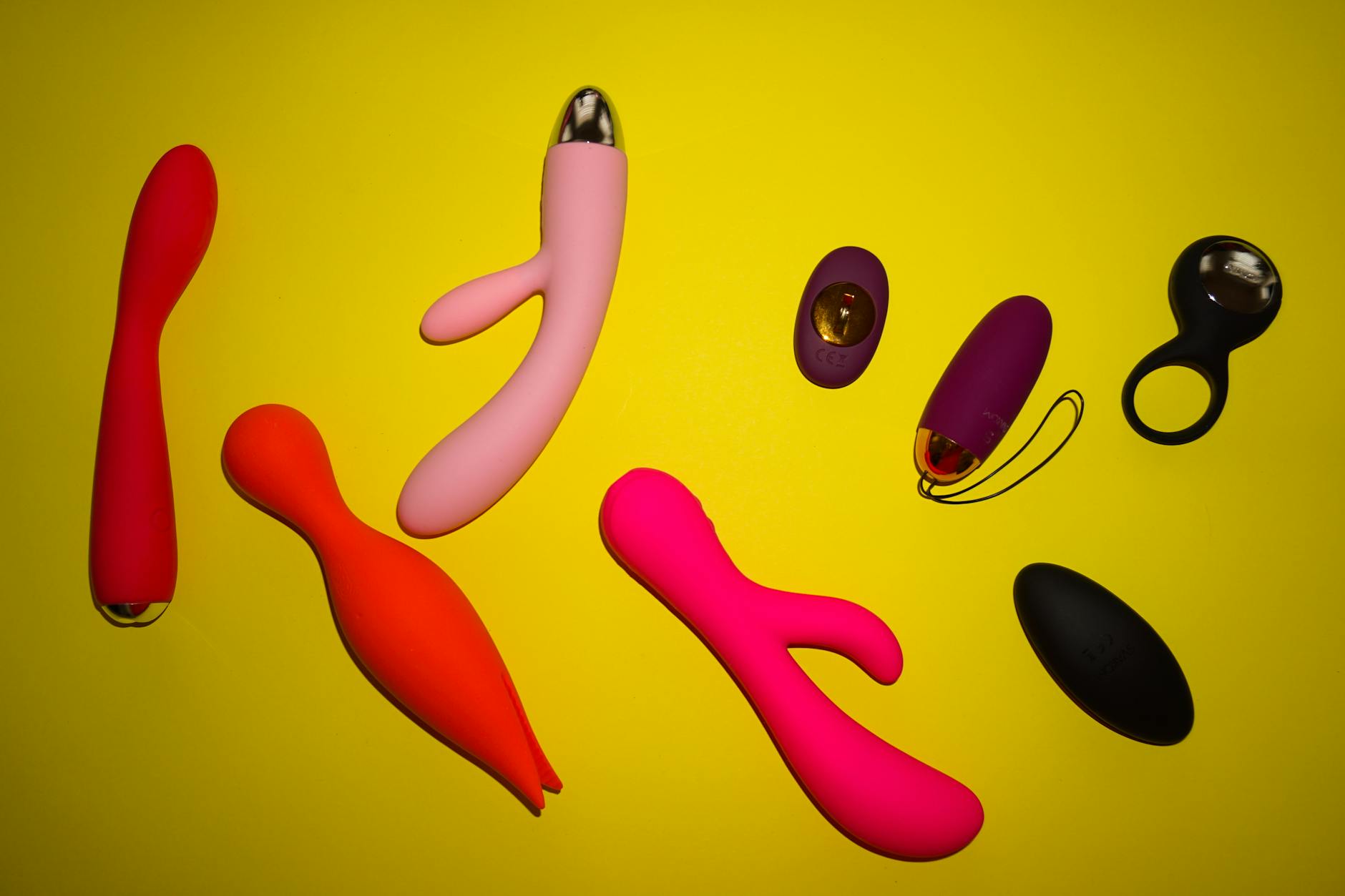 Colorful arrangement of various clitoral vibrators on a bright yellow surface