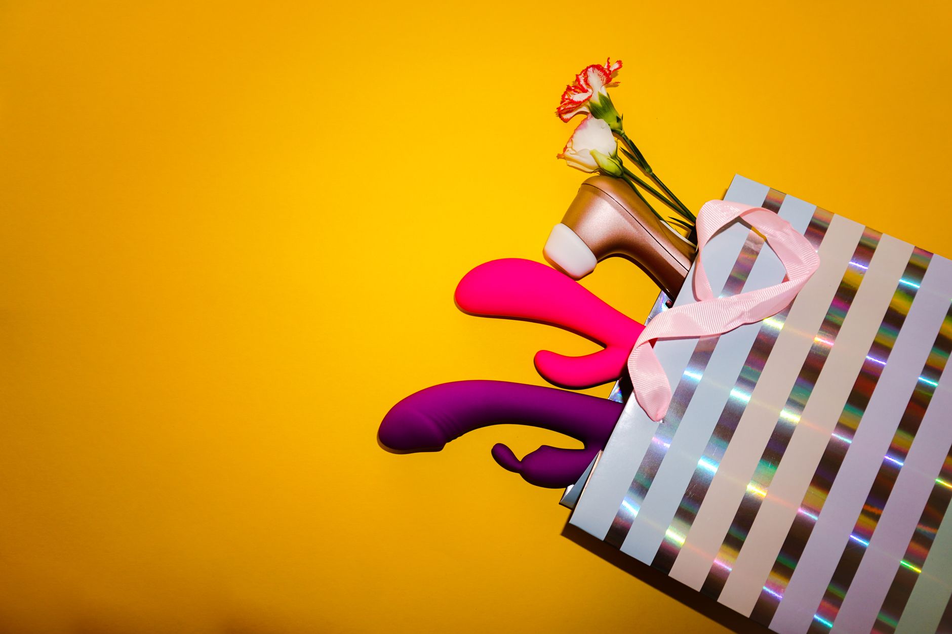 Collection of colorful vibrators including lemon clitoral vibrators arranged on a yellow background